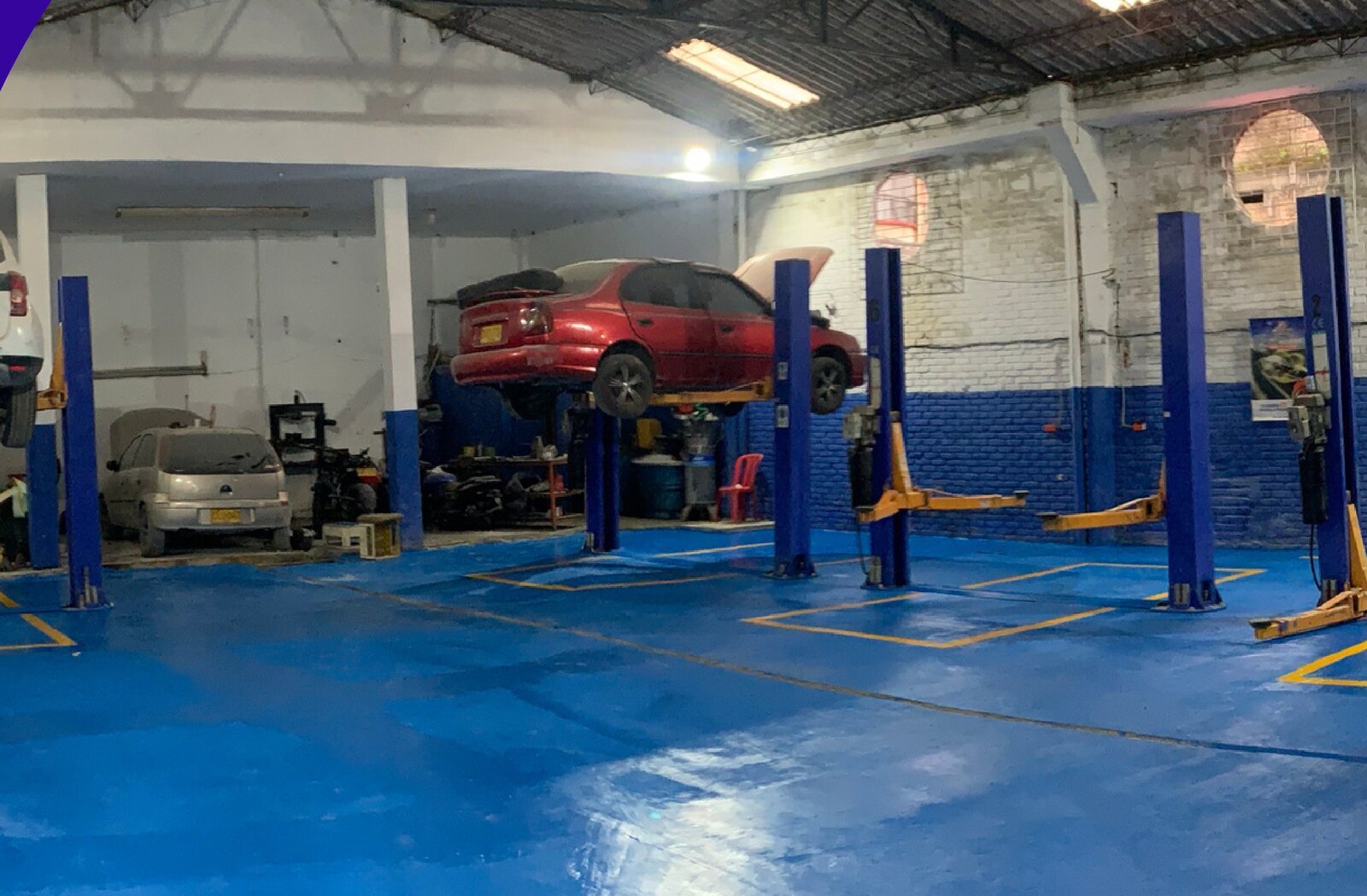 Interior del taller Servicios Integrales JNR: elevadores de dos columnas con vehículos en servicio